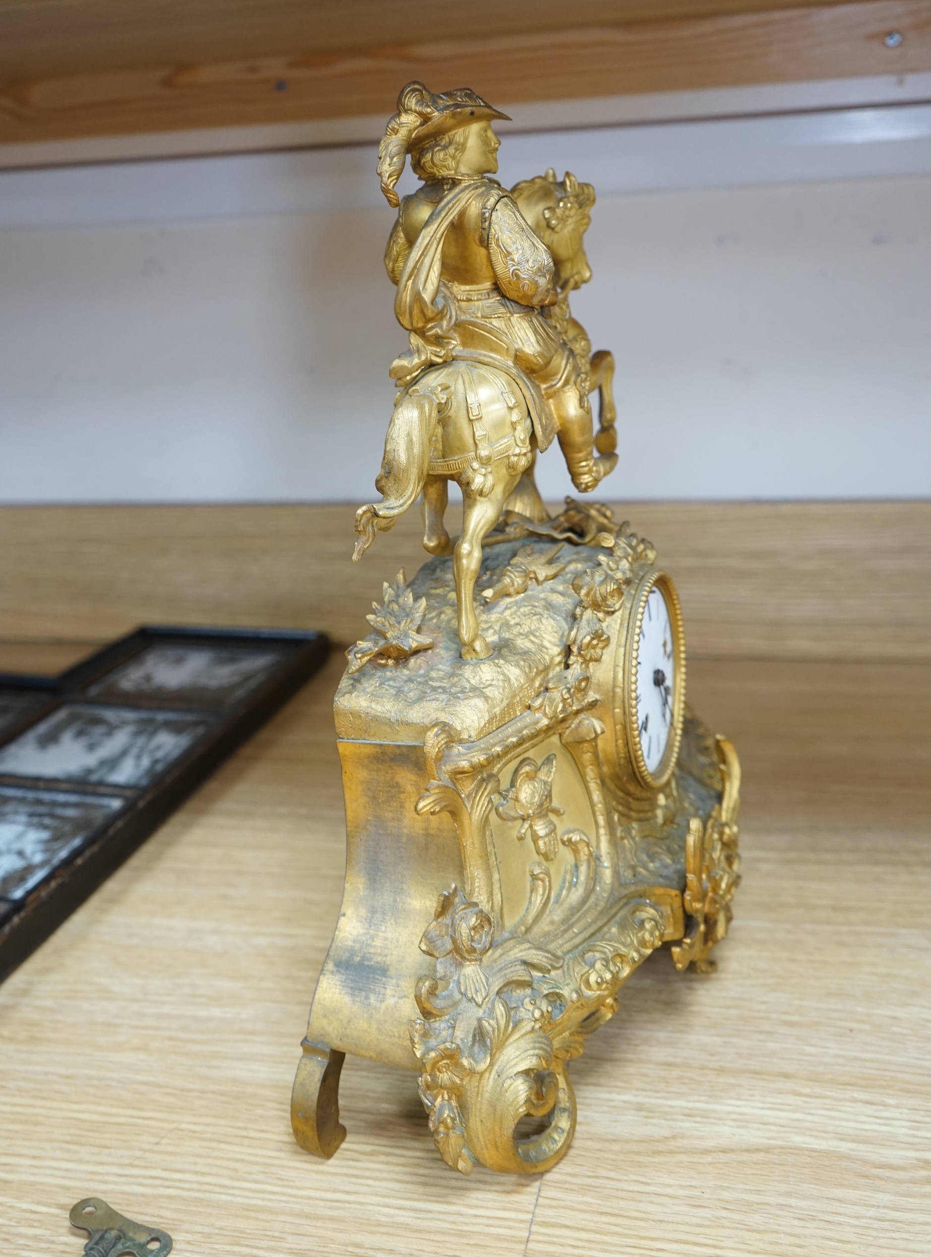 A late 19th century French ormolu mantel clock surmounted with a cavalier on horseback, key and pendulum, 38cm. Condition - fair to good